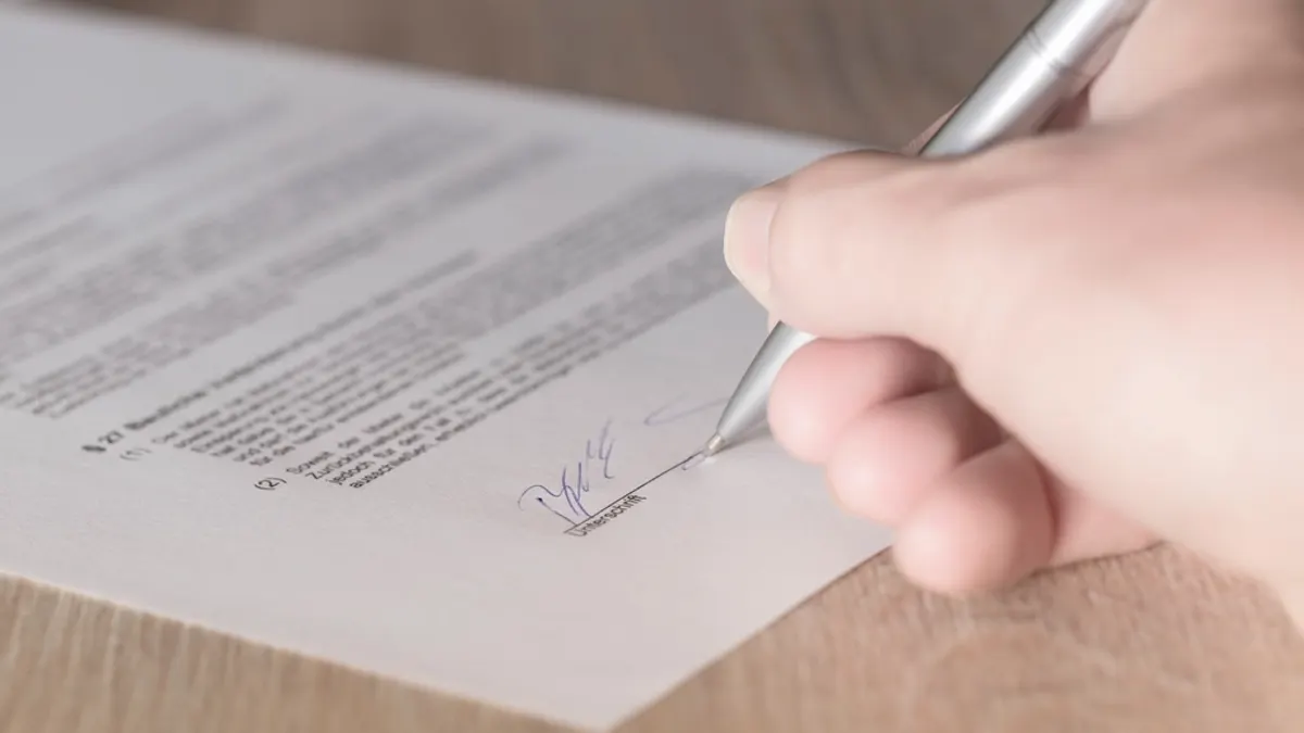 Hand zet met een pen een handtekening onder een gedrukt contract, waarin je annuleringsvoorwaarden vastlegt