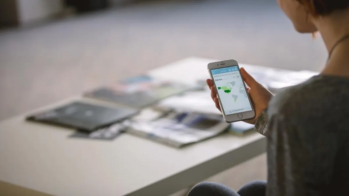 Vrouw aan tafel met telefoon, automatische mails naar gasten per boeking