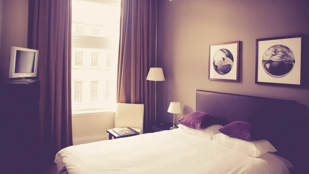 Tweepersoonsbed met paarse kussens in een aparte B&B-kamer bij het raam