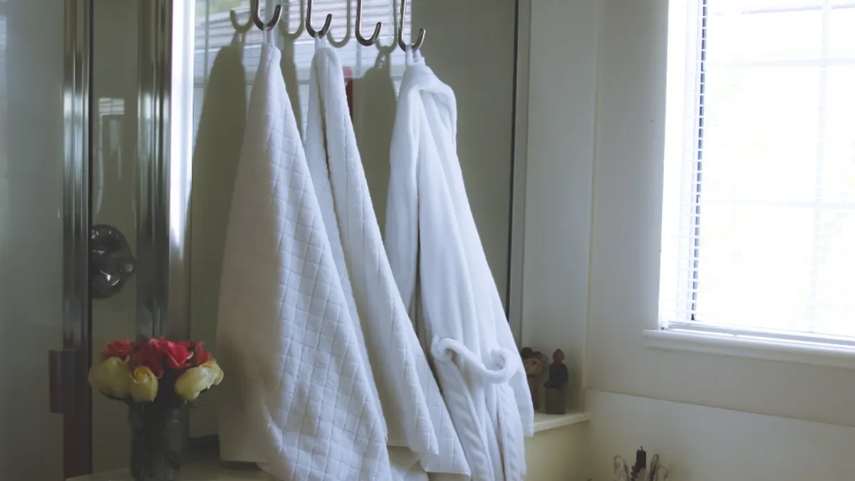 Witte badjassen en handdoeken aan haken in de badkamer, linnengoed dat je meerekent of laat bijboeken