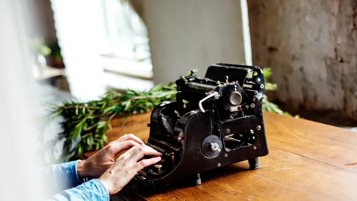 Hand typt op een typemachine de beschrijving van een vakantiehuis