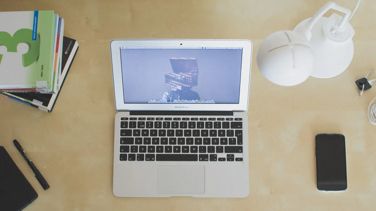 Laptop en smartphone naast elkaar op een licht bureau, waar je boekingen in Google Agenda bekijkt