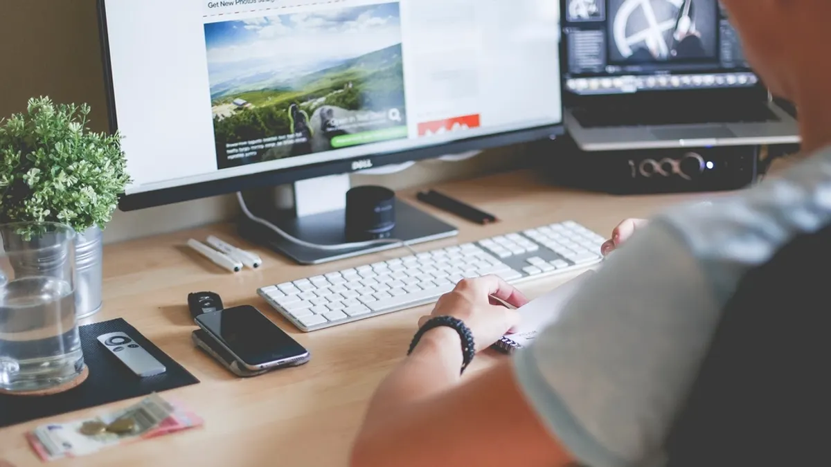 Hand aan het toetsenbord achter een beeldscherm met een website, waar je je boekingssite bouwt