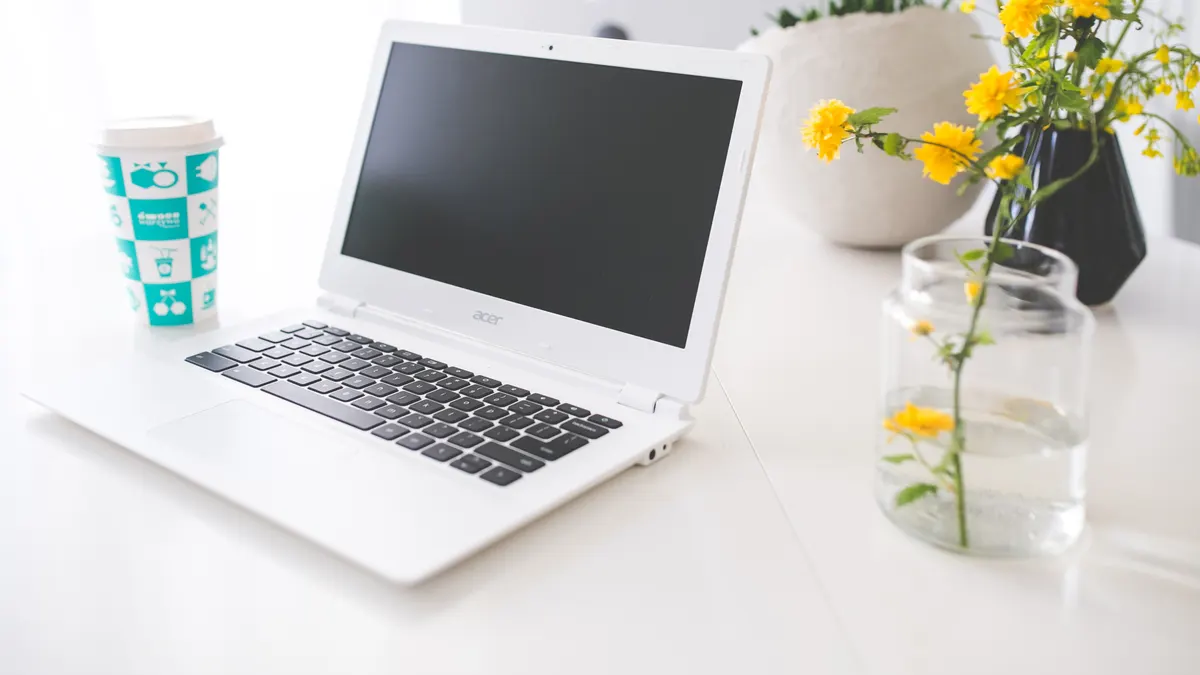 Opengeklapte witte laptop met donker scherm op een wit bureau, waar je de Booking.com-kalender koppelt