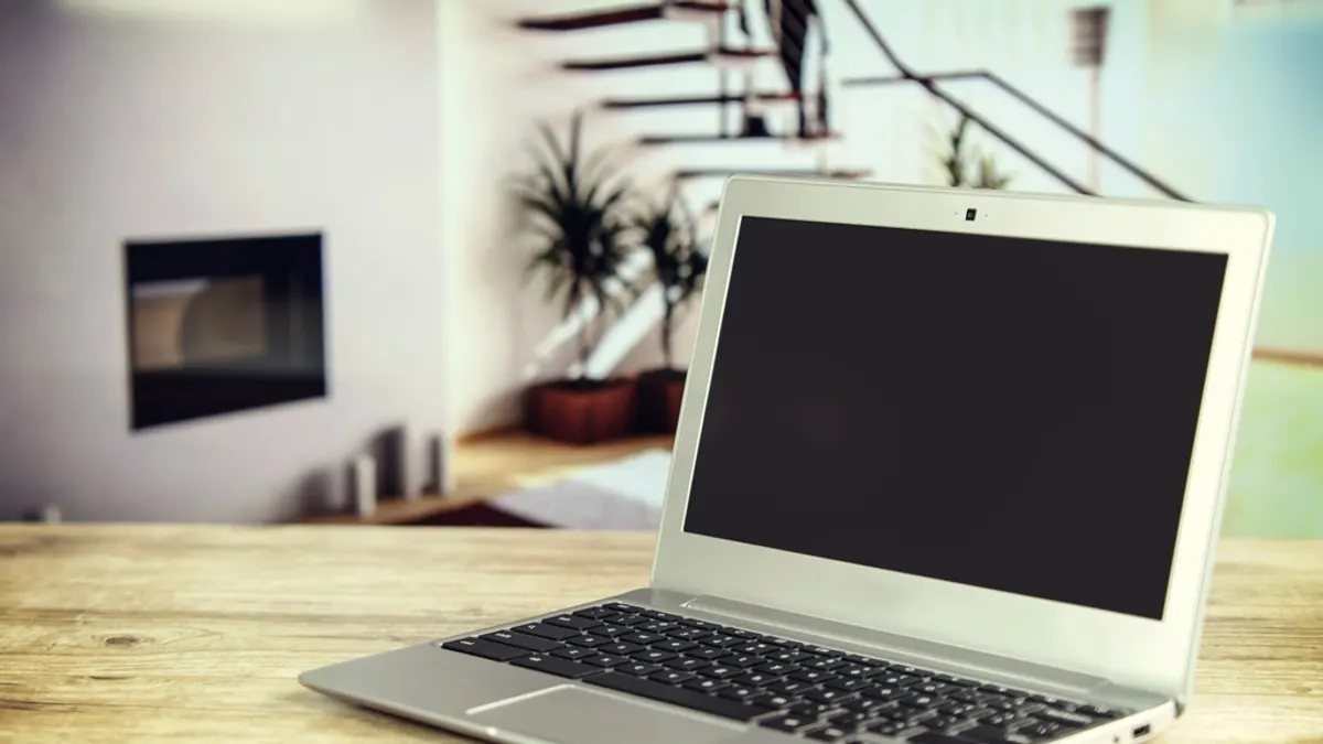 Laptop met donker scherm op een houten tafel, waar je de kalenders van één vakantiehuis bijhoudt