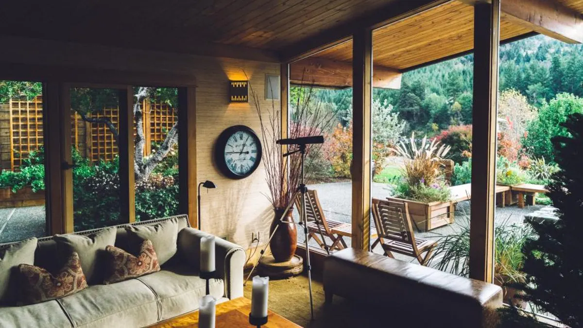 Ronde wandklok in een houten woonkamer met bank, waar de check-intijd van een vakantiehuis ingaat