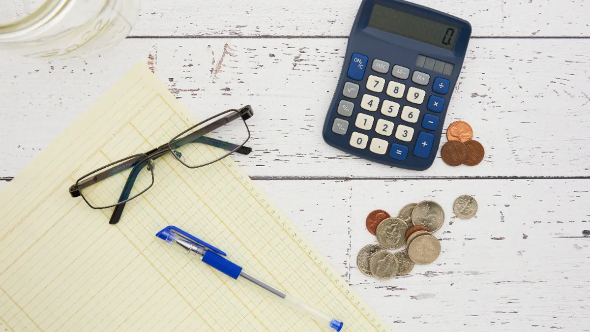 Rekenmachine, notitieblok en munten voor het opstellen van een factuur voor vakantieverhuur