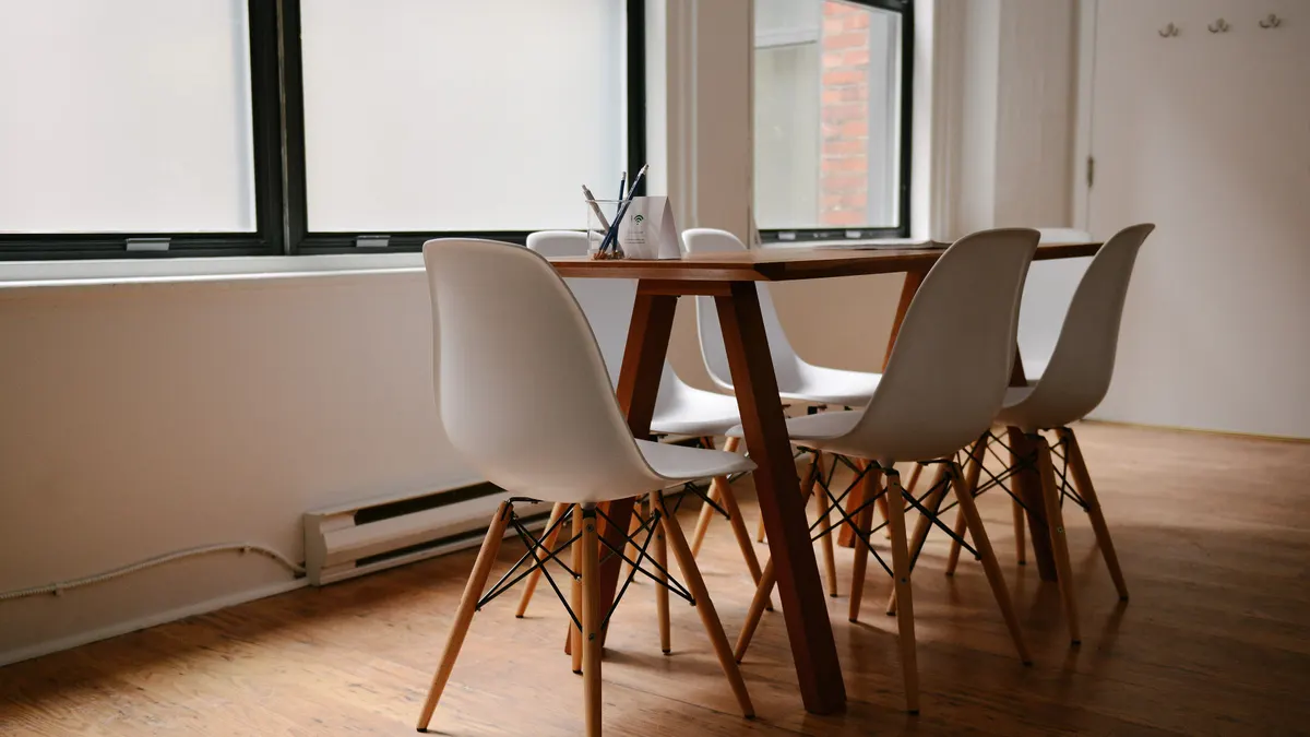 Witte stoelen rond een houten tafel, waar je de nachtprijs per persoon voor een groep rekent