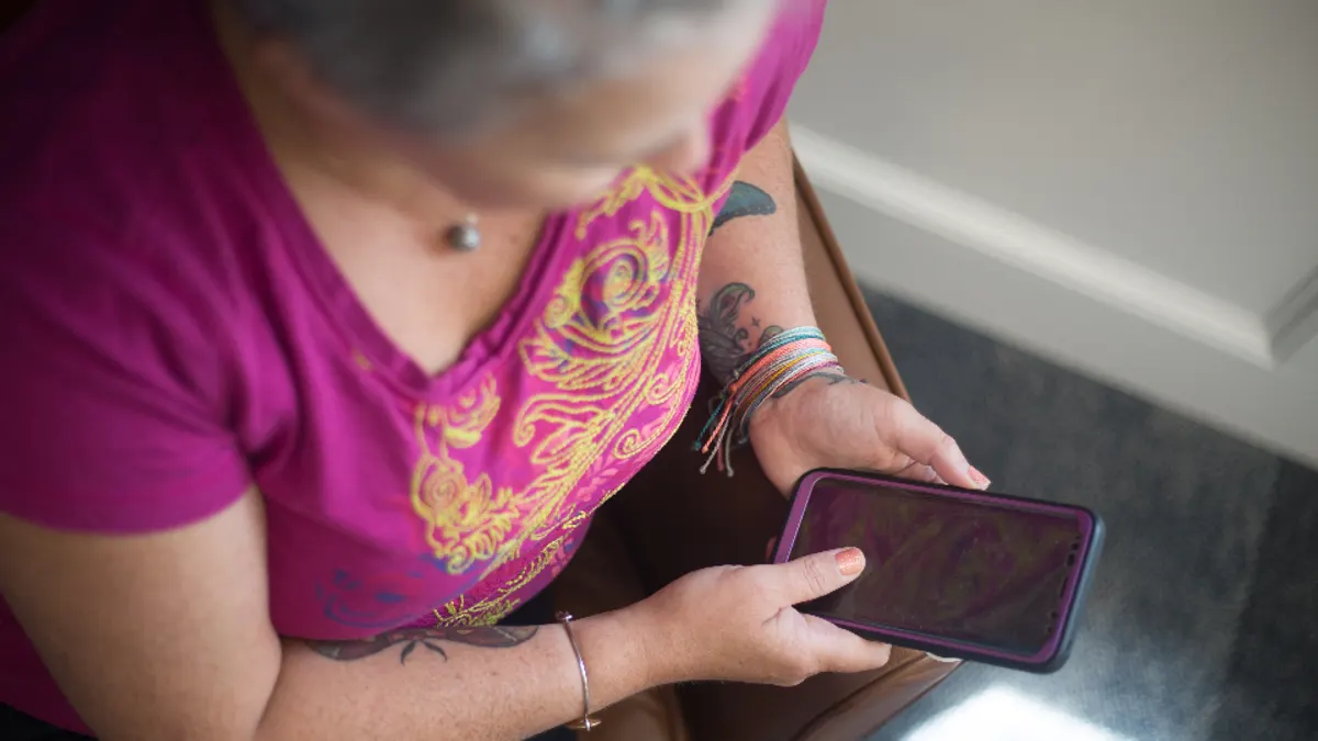 Vrouw in een roze shirt kijkt op haar telefoon, waarmee je een aanvraag snel beantwoordt