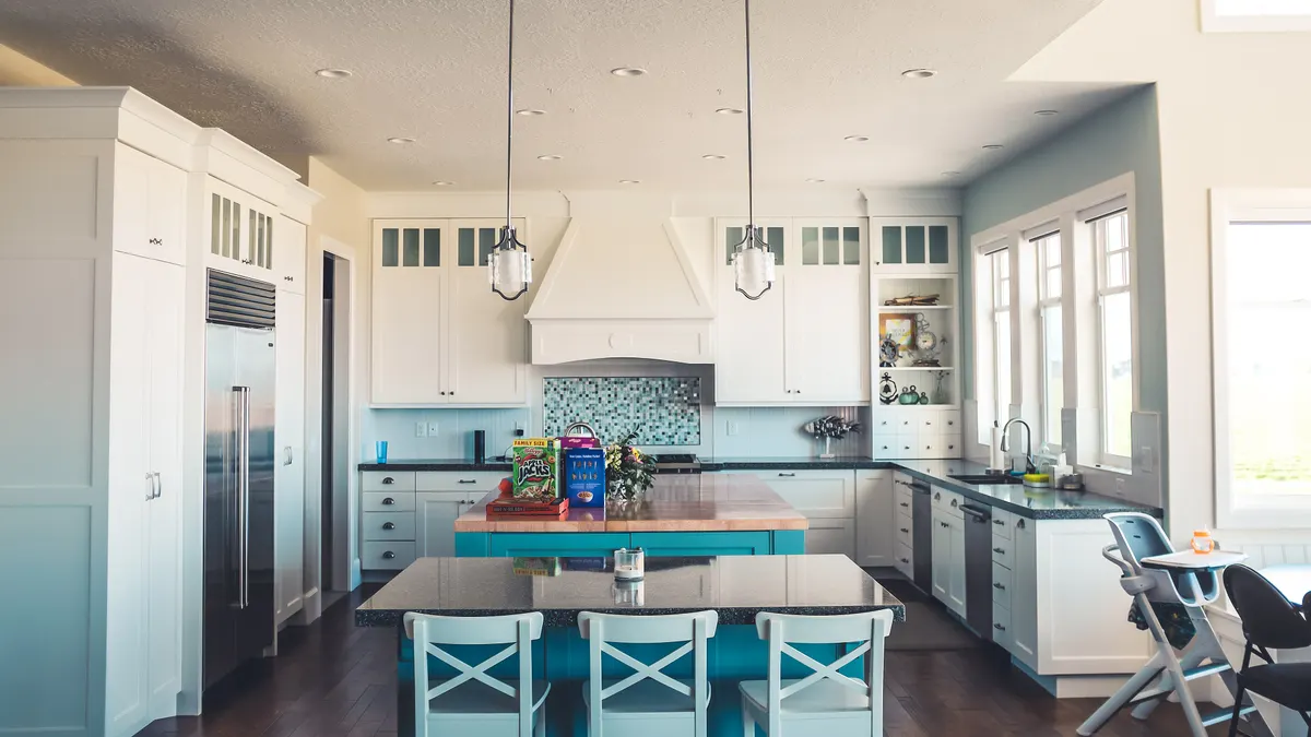 Keukeninventaris van een vakantiehuis: witte kasten, turquoise eiland en eettafel