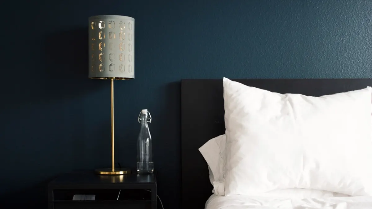 Opgemaakt bed met wit beddengoed tegen een donkerblauwe muur, klaar voor een lastminuteboeking in een lege week