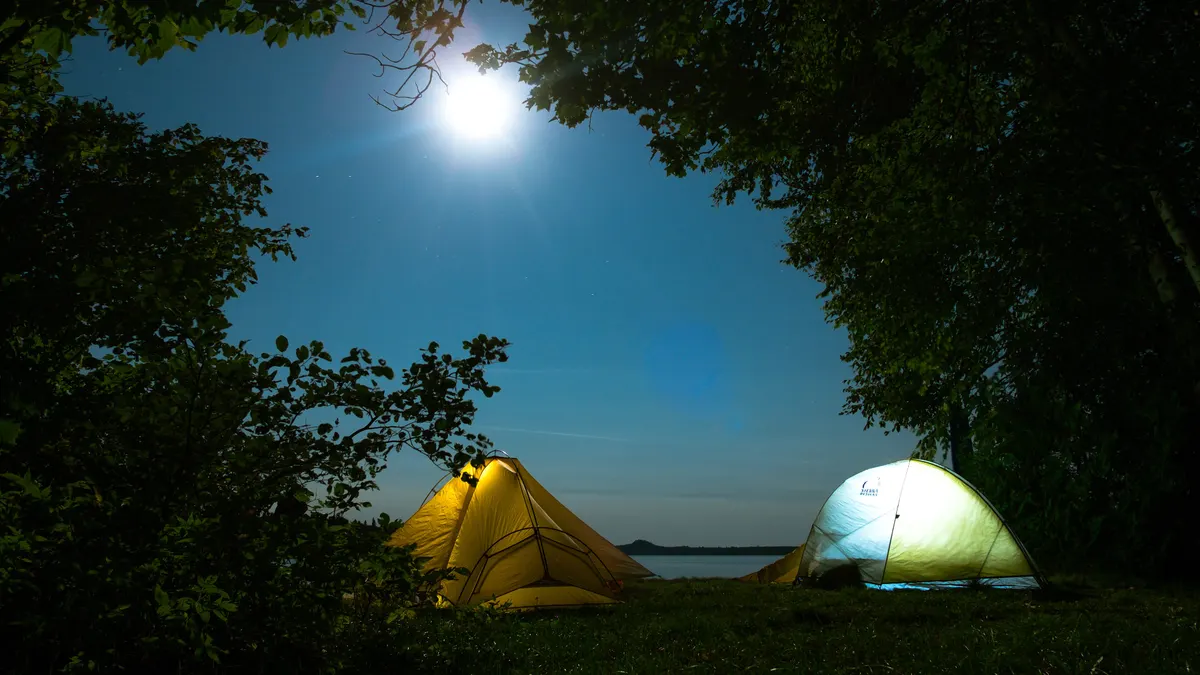 Twee verlichte tenten op grasveld, kampeerplaatsen van een kleine minicamping