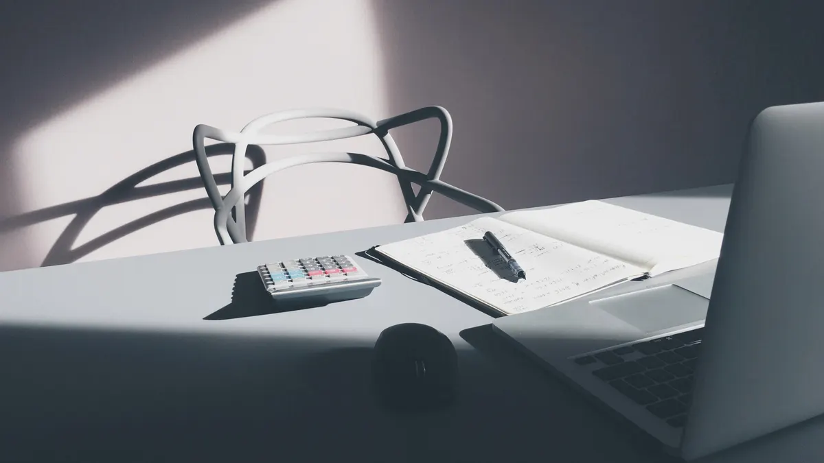 Rekenmachine, notitieblok en laptop op een bureau om de nachtprijs te berekenen
