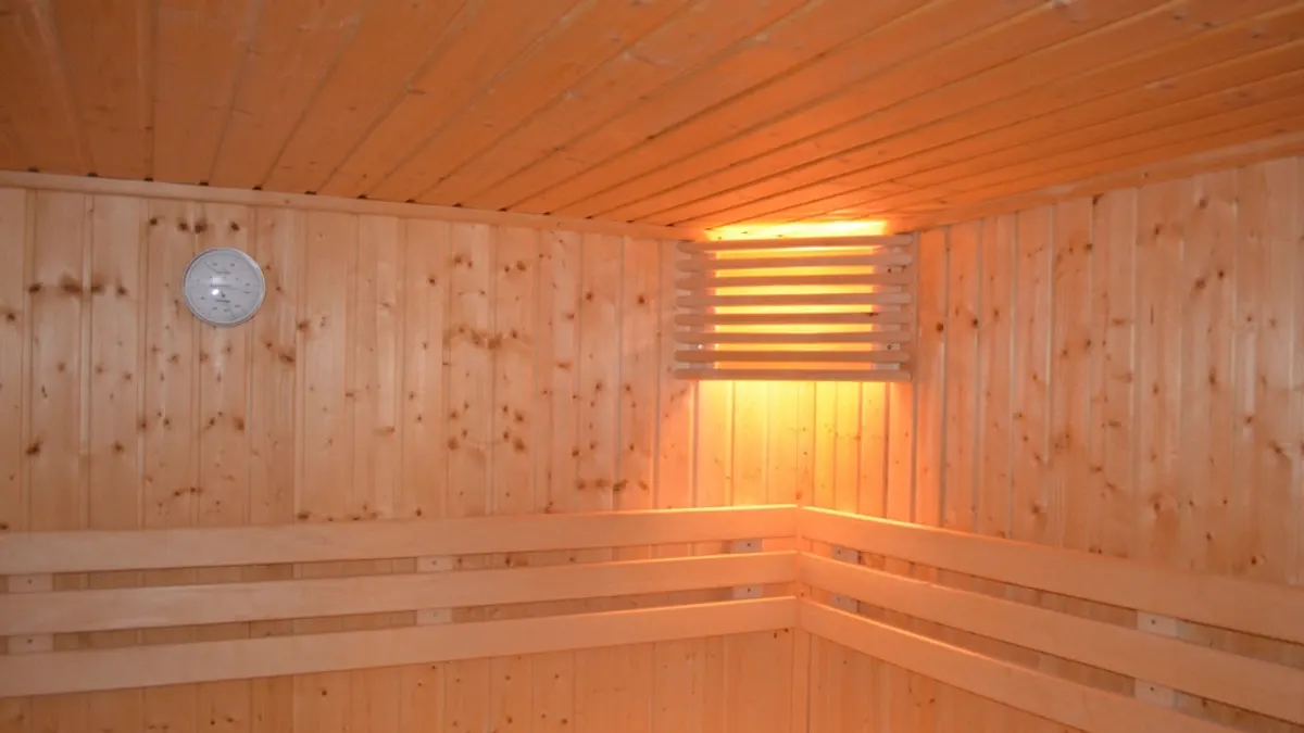 Lege houten sauna met banken en warm licht achter een lattenkap, als extra bij een verblijf