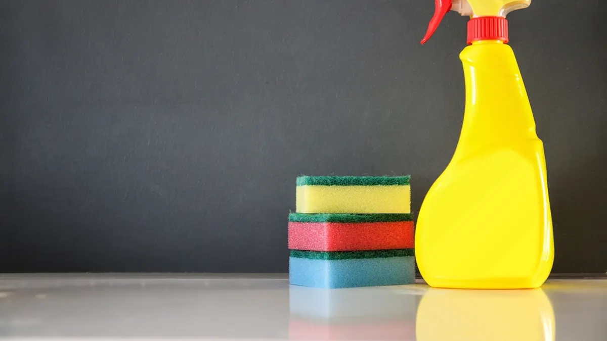 Gele sprayfles en gekleurde sponzen voor de eindschoonmaak van een vakantiewoning