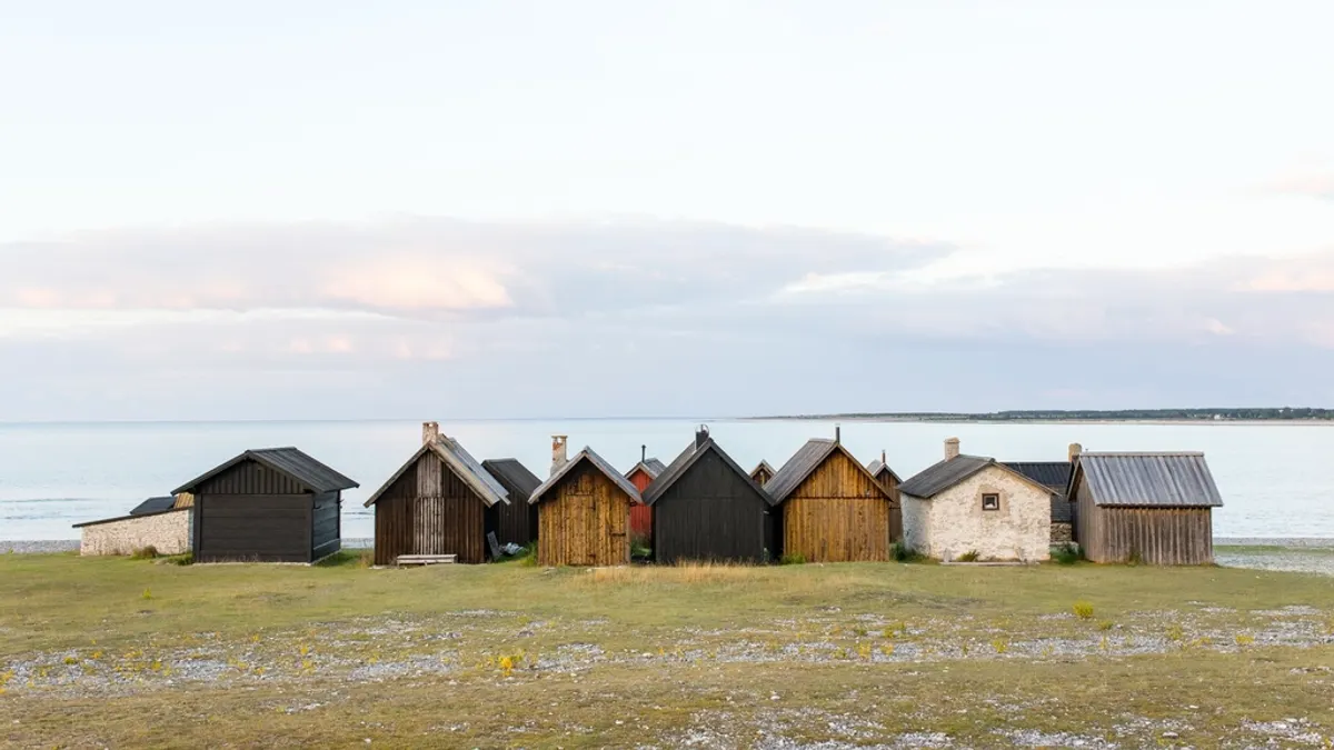 Houten huisjes op een rij aan zee, zoals een tiny house dat je per nacht verhuurt