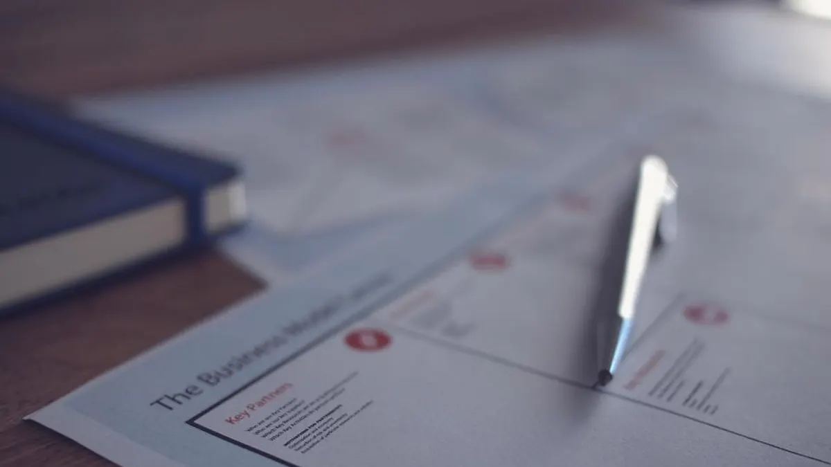 Uitgeprint formulier met pen en blauw notitieboek op een bureau, waar je je verhuurpolis naloopt