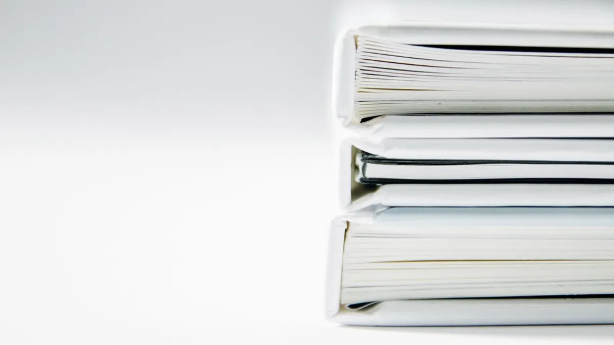 Drie witte gebonden boeken op elkaar, de vorm waarin praktische informatie voor gasten vaak belandt